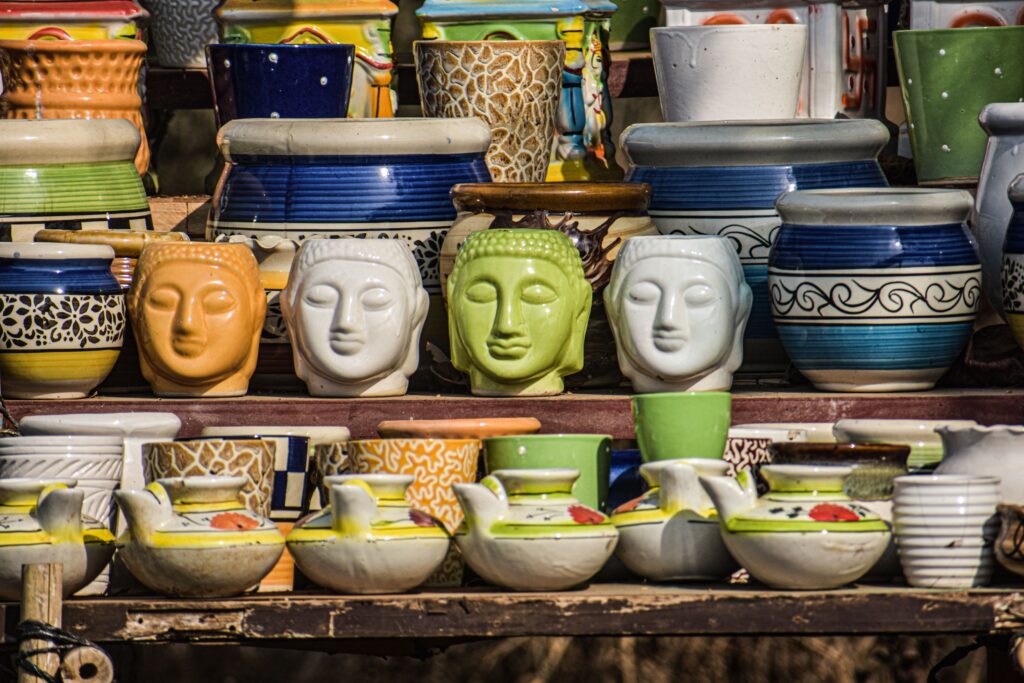 Vibrant ceramic pots with face designs on display in a market in Navi Mumbai, India.